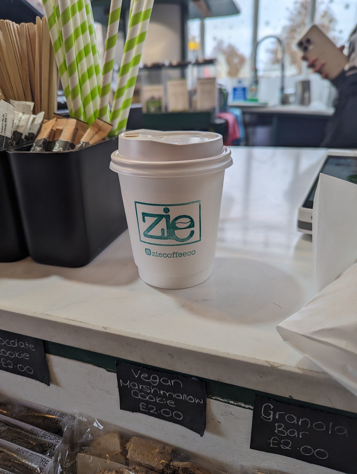 The counter with paper straws and stirrers beside a takeaway cup