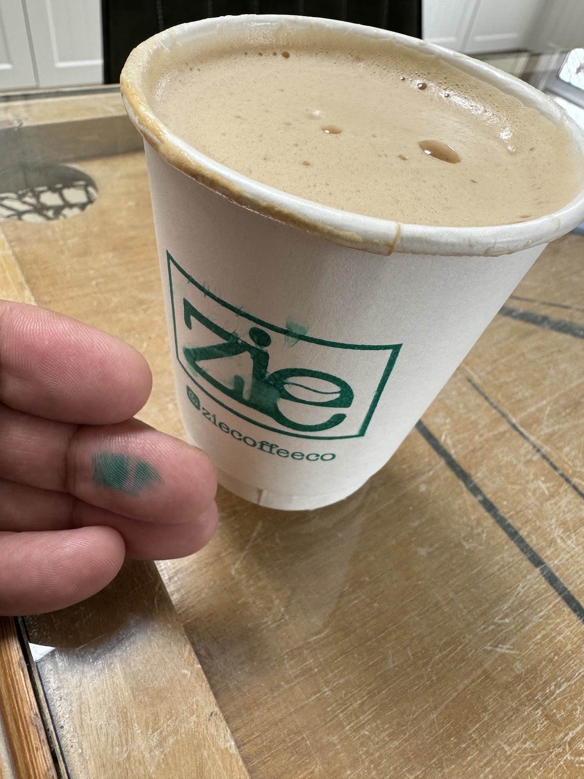 A cup of coffee with a thick crema, held over a wooden table