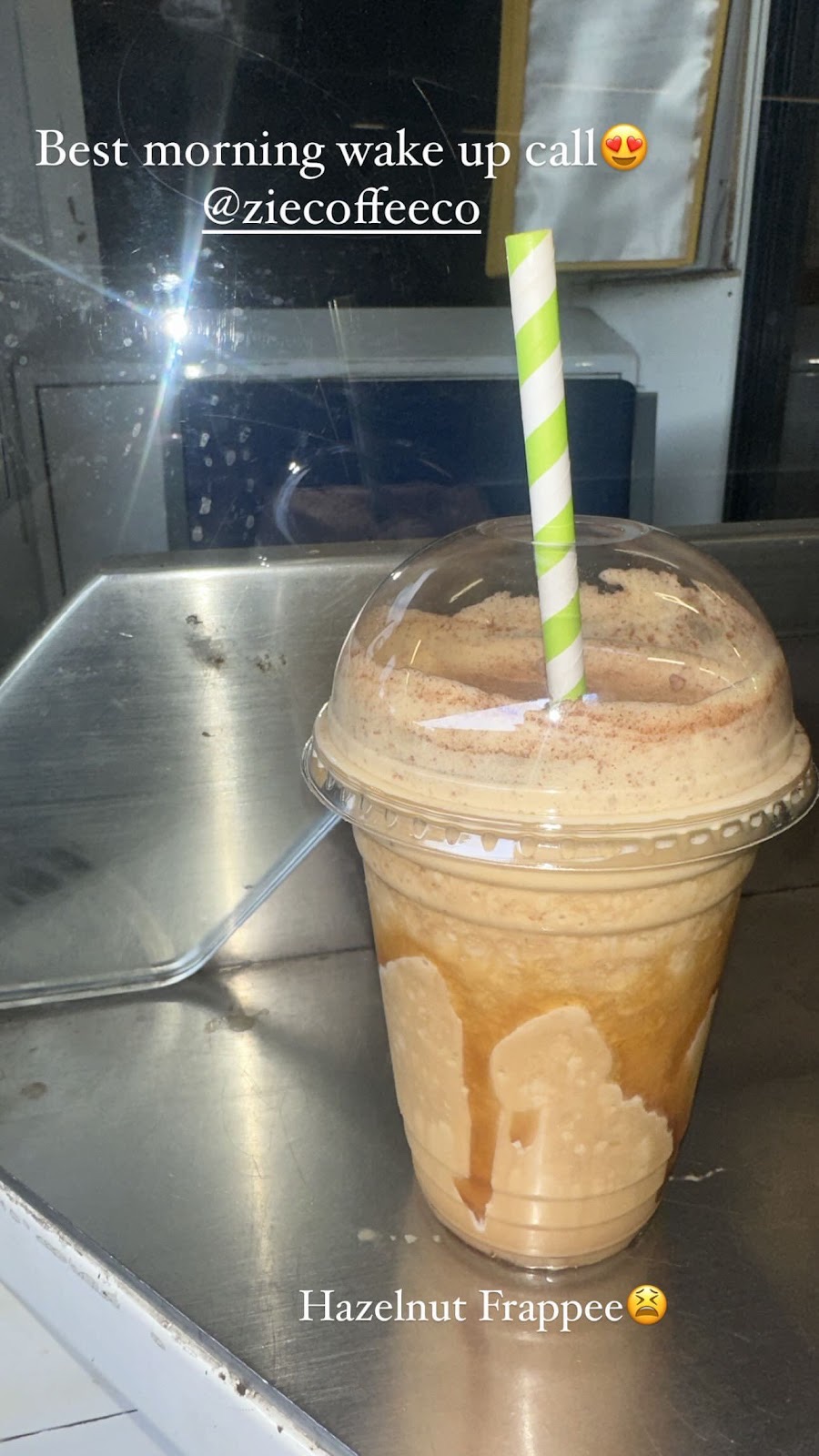 A hazelnut frappe in a clear cup with a striped straw